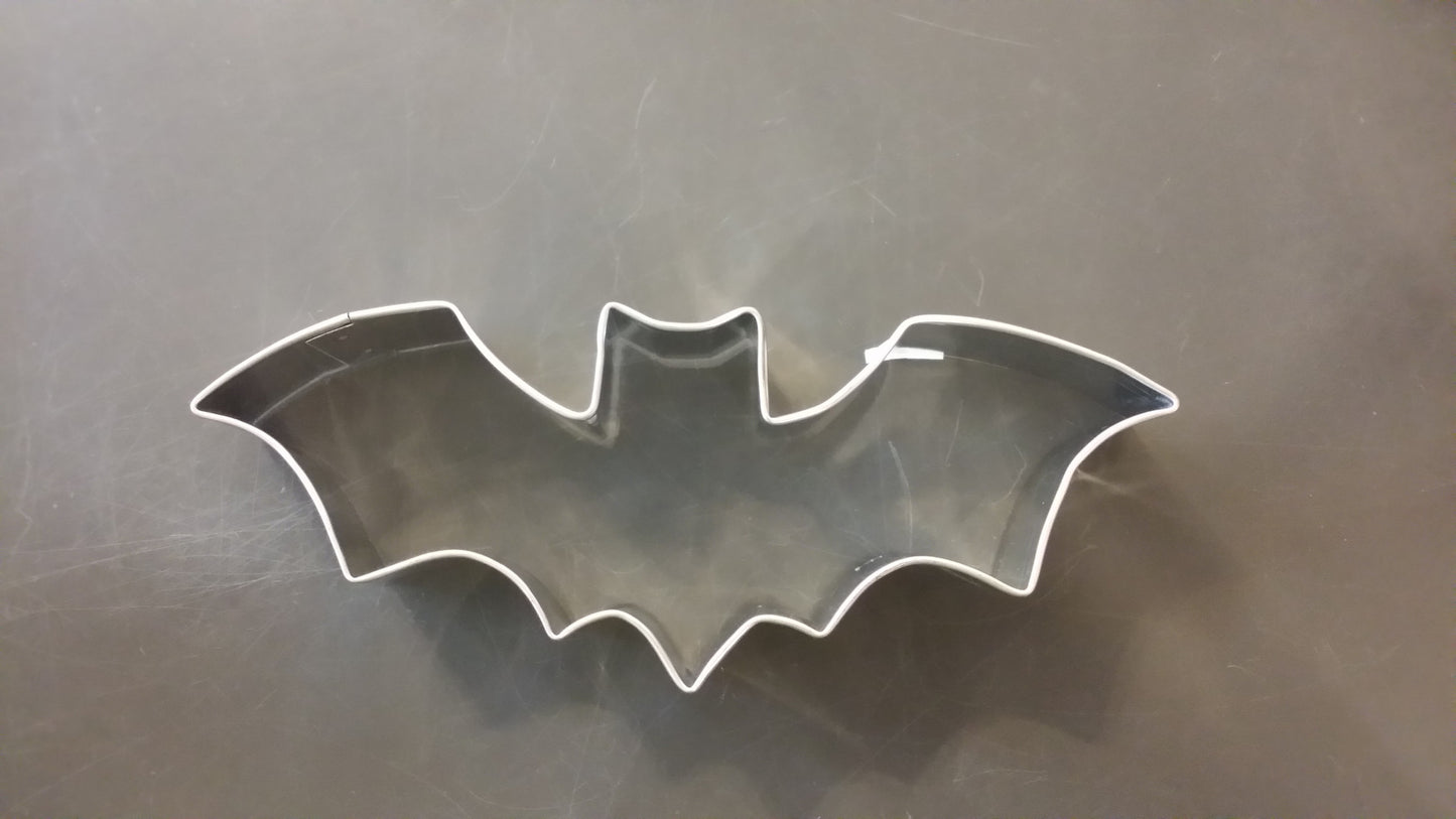 Metallic bat-shaped cookie cutter on a reflective surface