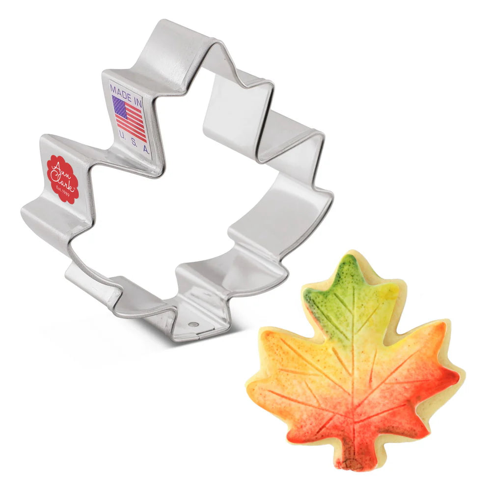 Leaf-shaped cookie cutter with a cookie shaped like a leaf on a white background