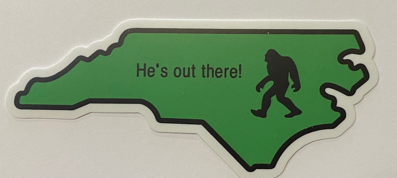 A green vinyl decal in the shape of North Carolina with a picture of Sasquatch and the text 'He's out there!'