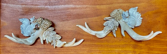 Set of two white squirrel wall hangings with detailed antlers,squirrels, and leaves.