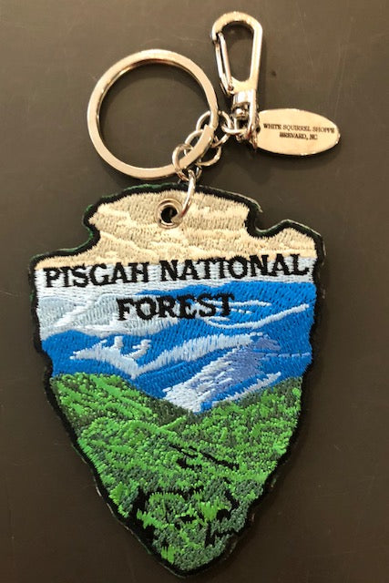Embroidered key chain in the shape of an arrowhead with a mountain scene and 'Pisgah National Forest' on it.