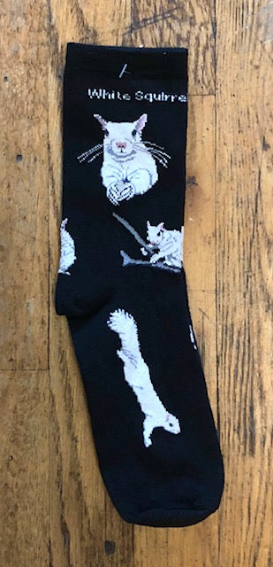 A pair of socks with a black background and a pattern of white squirrels and their tails.