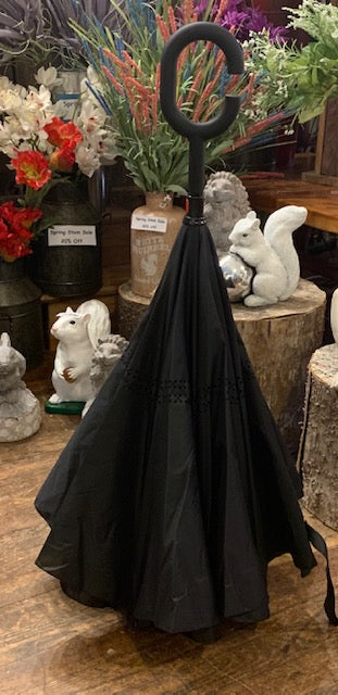 Inverted style umbrella shown closed. Black with repeating white squirrel pattern on the outside when opened.