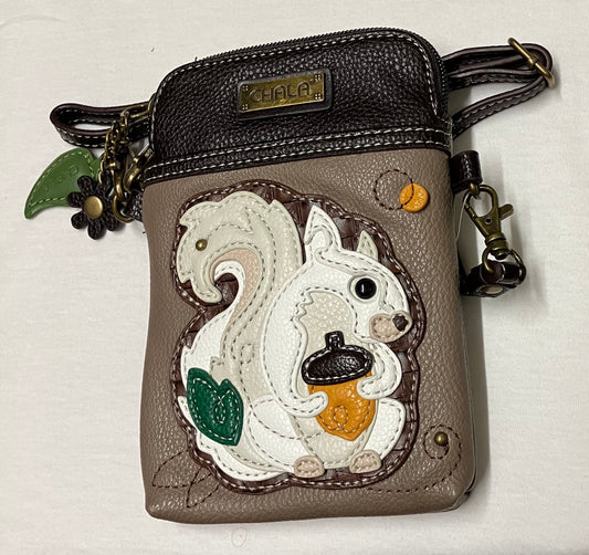 A small Chala crossbody wallet in taupe and dark brown faux leather, featuring a large applique of a white squirrel holding an acorn on the front pocket.