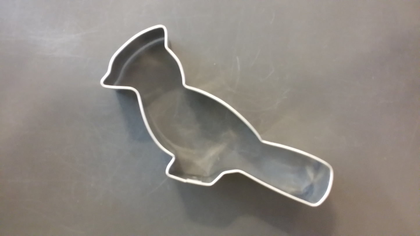 Metallic bird-shaped cookie cutter on a reflective surface