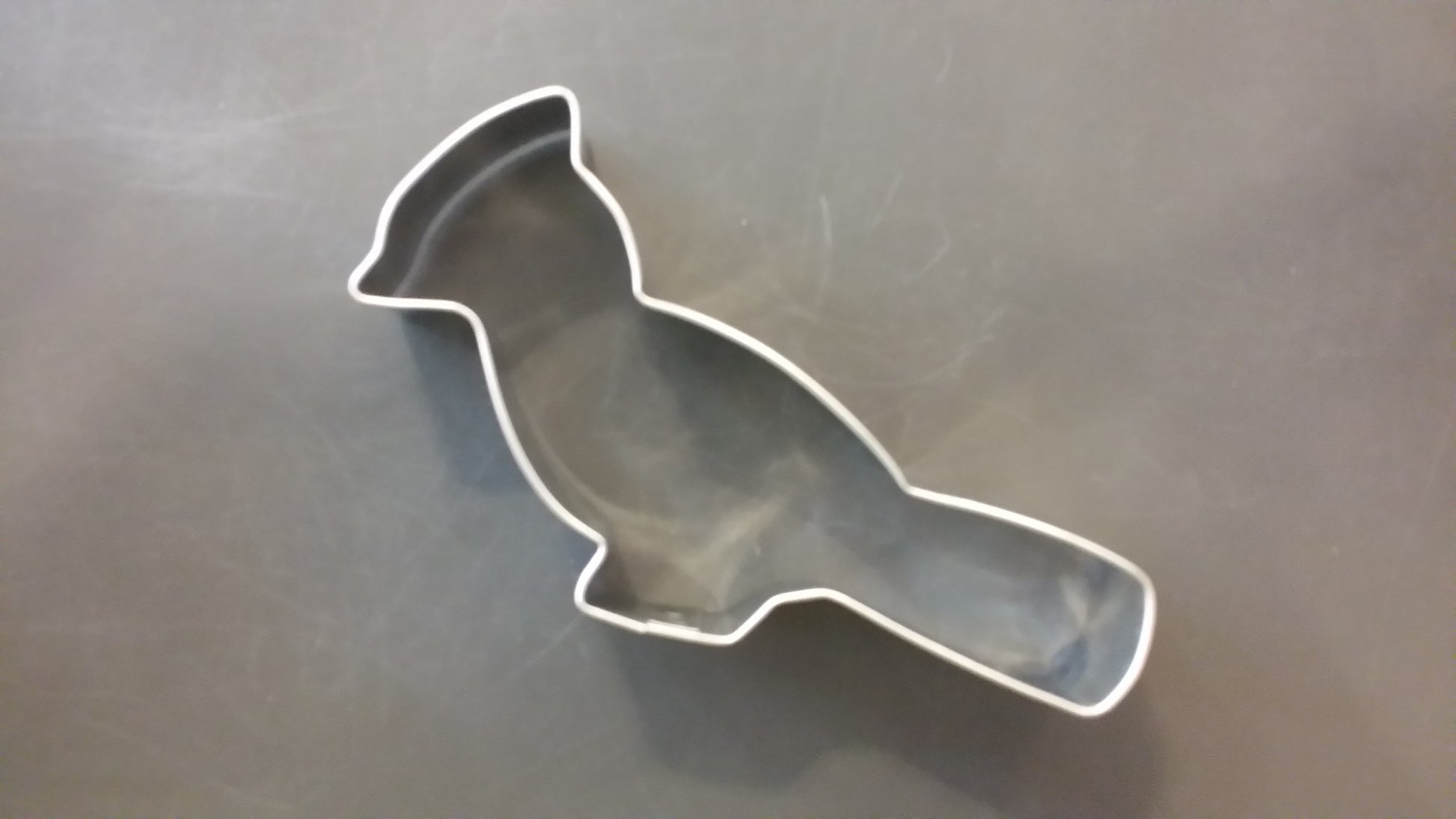 Metallic bird-shaped cookie cutter on a reflective surface