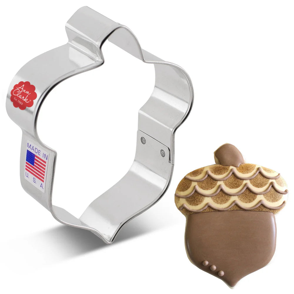 Acorn-shaped cookie cutter with a decorated acorn cookie on a white background