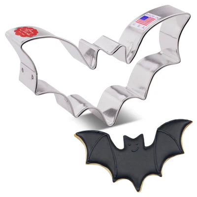 Bat-shaped cookie cutter with a black bat-shaped cookie on a white background