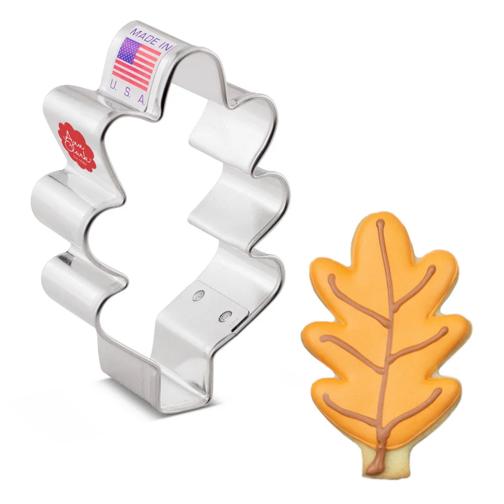 Silver leaf-shaped cookie cutter with a leaf-shaped cookie on a white background