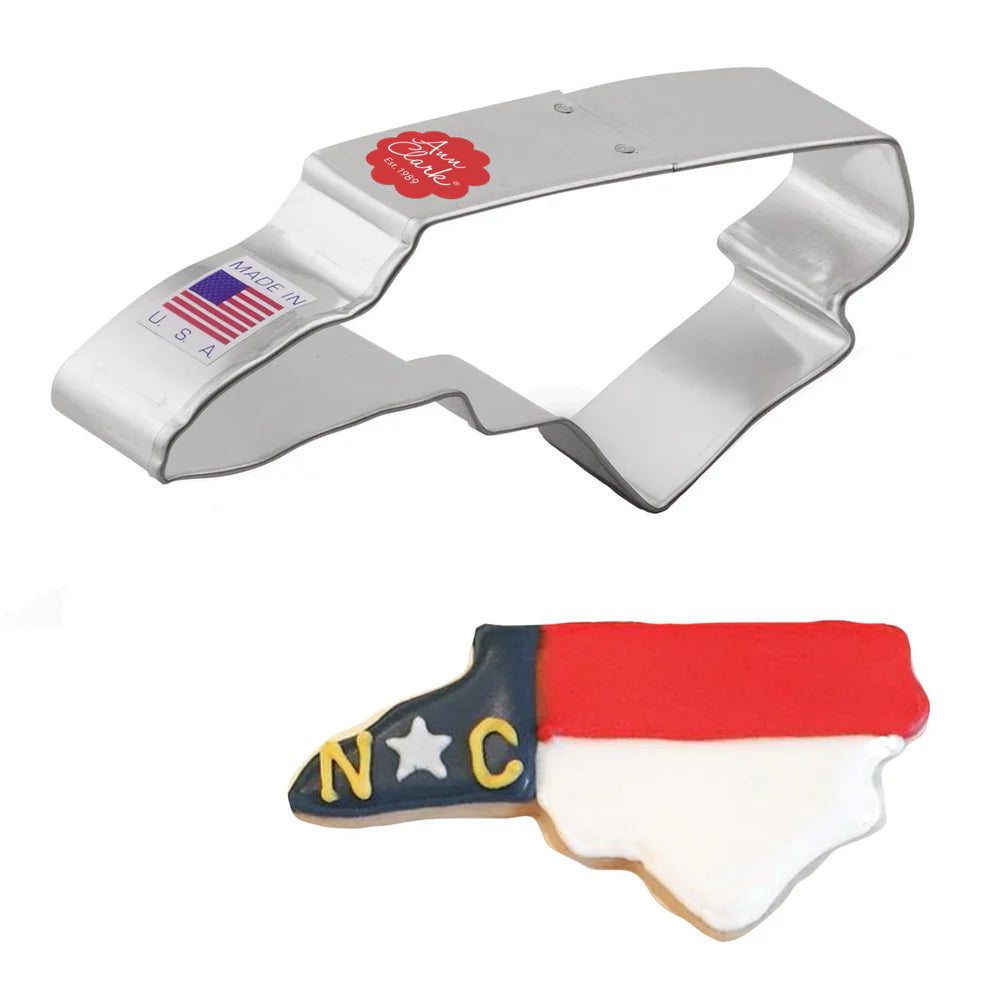 Cookie cutter shaped like the state of North Carolina with a cookie cut out on a white background