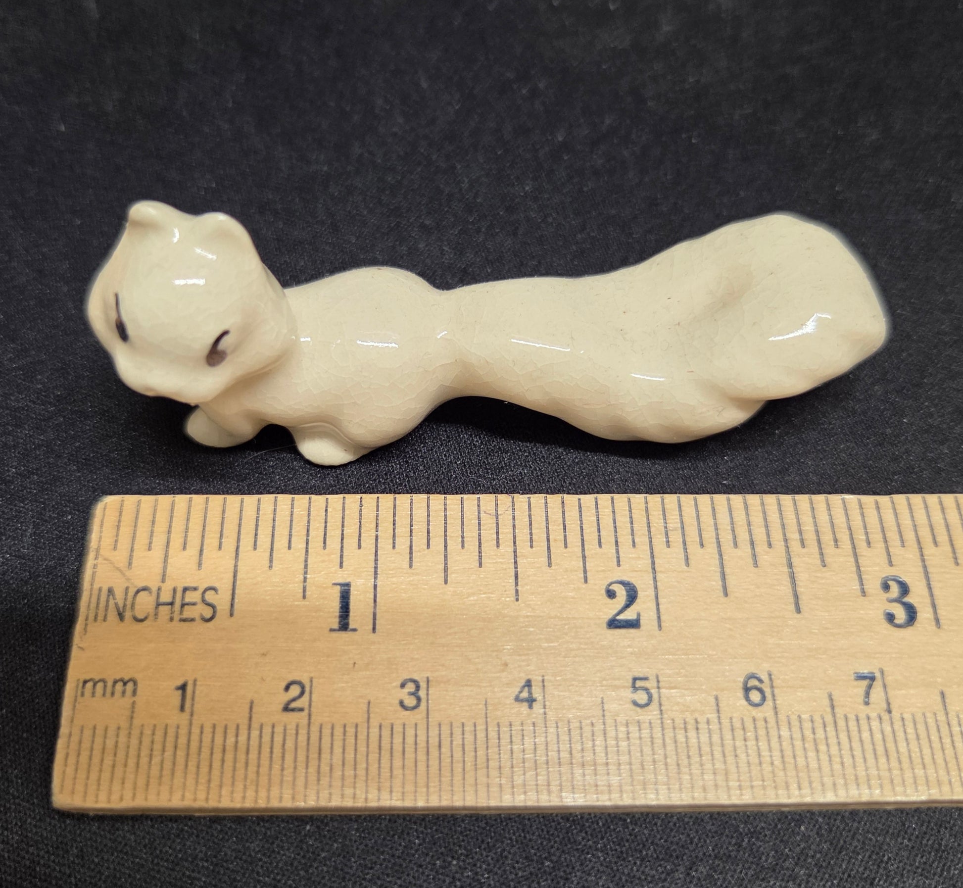 White ceramic animal figurine displayed next to a ruler for sizing.