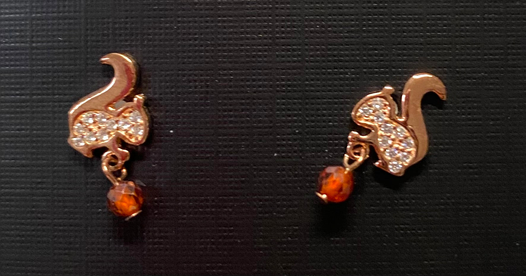 A pair of rhinestone stud earrings designed to look like squirrels with brown rhinestone acorns.