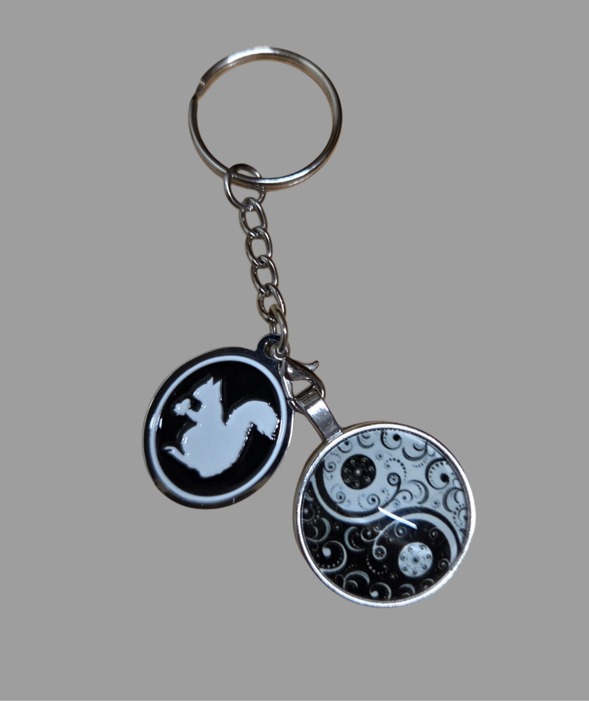 Keychain with yin yang  and white squirrel on a gray background