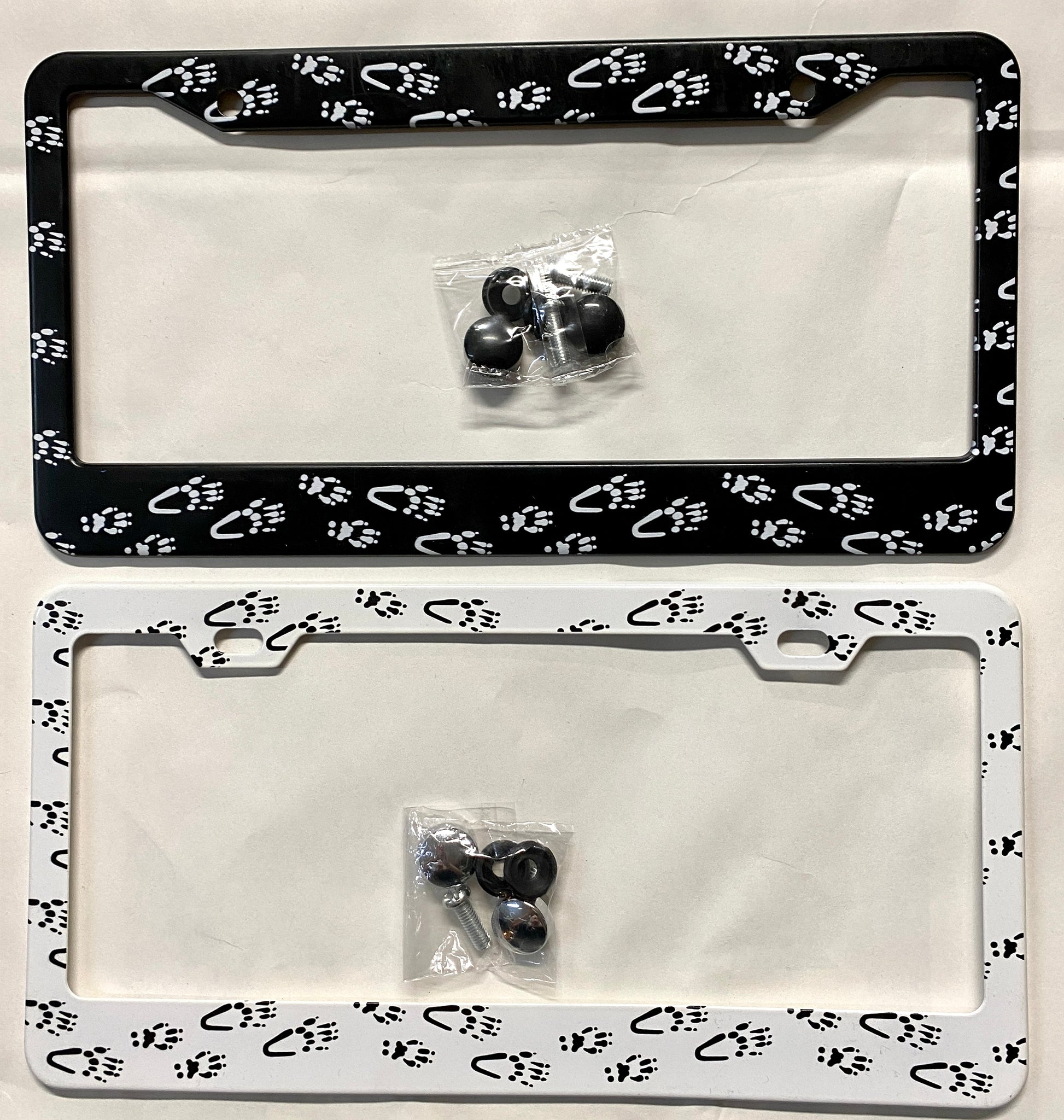 Two aluminum license plate holders with white and black squirrel paw prints design, including mounting hardware.