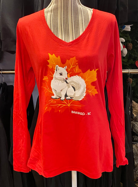 A red long-sleeve v-neck ladies t-shirt displayed on a mannequin, featuring a graphic of a white squirrel sitting in autumn leaves.