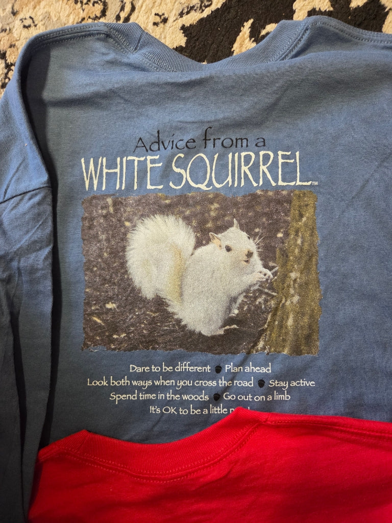 Blue t-shirt with a white squirrel graphic and text on a wooden surface