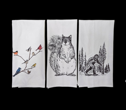 Three folded towels with nature-themed designs on a black background