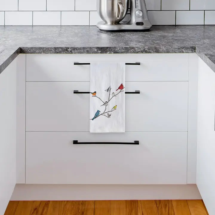 Kitchen with white cabinets, black handles, and a decorative towel hanging on a cabinet door.