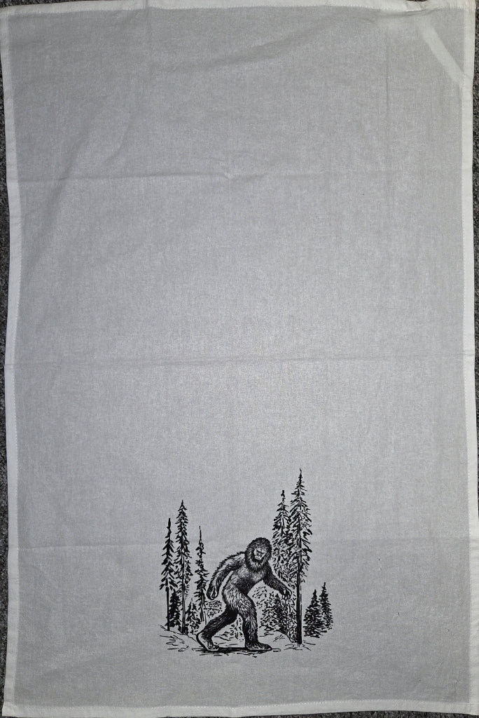 Tea towel with a black and white illustration of a bear and trees on a light gray background