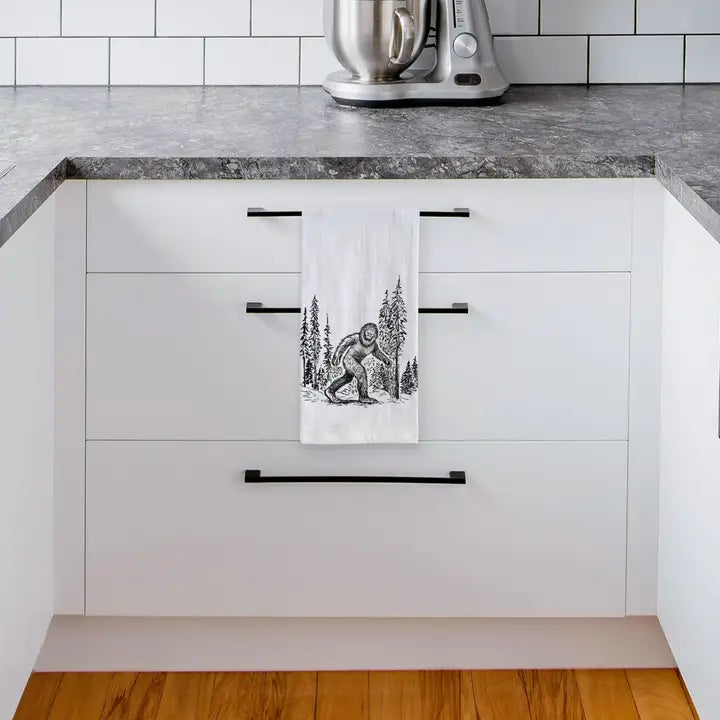 Kitchen with white cabinets, black handles, and a towel with a bear design hanging on one of the cabinets.