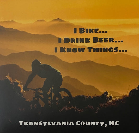 A vinyl decal with a silhouette of a person biking over mountains during sunset. Text on the decal reads 'I Bike... I Drink Beer... I Know Things...'.