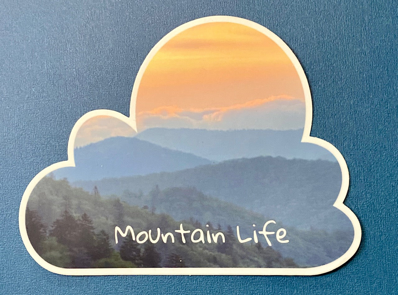 A vinyl decal with a mountain life sunset scene, shaped like a cloud, with the text 'Mountain Life' across the bottom.
