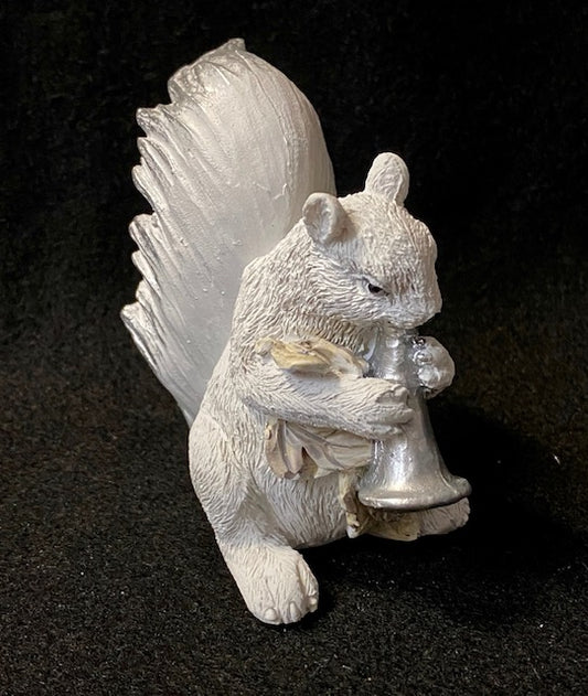 A white squirrel resin figurine is playing a trumpet.