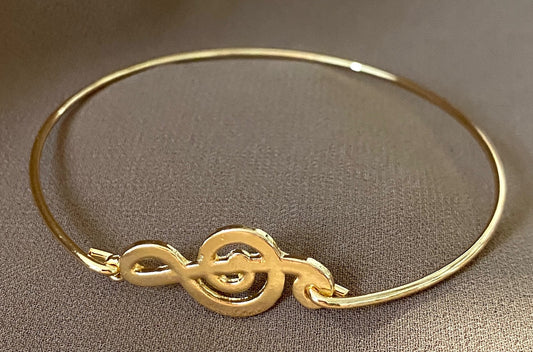 A gold alloy bracelet with a treble clef embellishment.