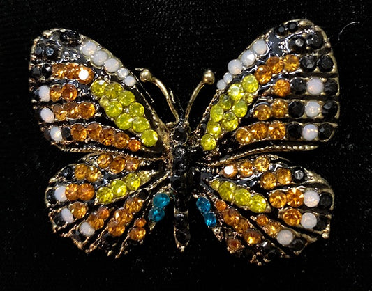 A colorful crystal monarch butterfly brooch with black, orange, yellow, and blue hues.