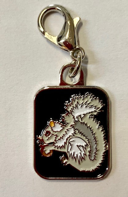 A charm featuring a white squirrel with a black background, attached to a lobster claw clip.