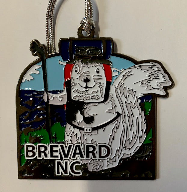 A two-sided metal ornament with a white squirrel hiking in Brevard, NC. Backpack and walking stick, this little white squirrel is ready to go.