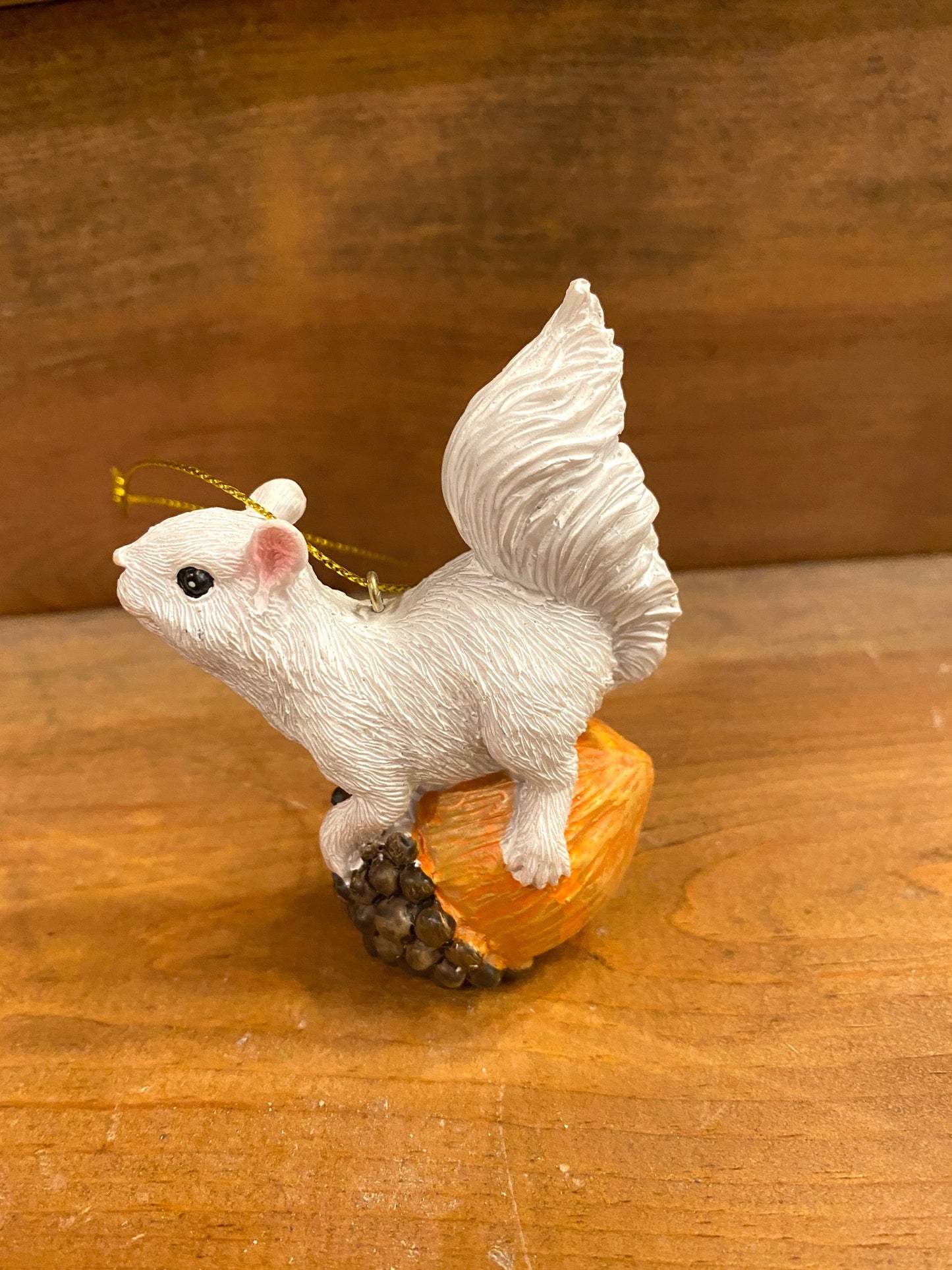 Cute ornament with a white squirrel perched atop an acorn. Gold loop for hanging.