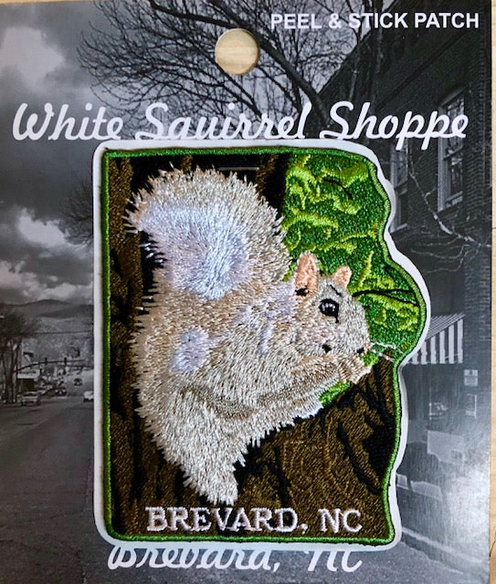 Embroidered patch depicting a white squirrel on a limb, with green leaves. The patch is peel and stick, from the White Squirrel Shoppe.