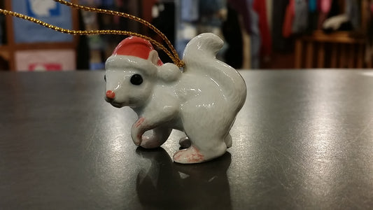 A hand painted, white squirrel ornament wearing a red Santa hat.