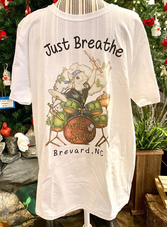 White crew neck t-shirt with short sleeves featuring an illustration of a white squirrel playing the drums, along with the text 'Just Breathe' and 'Brevard, NC'.